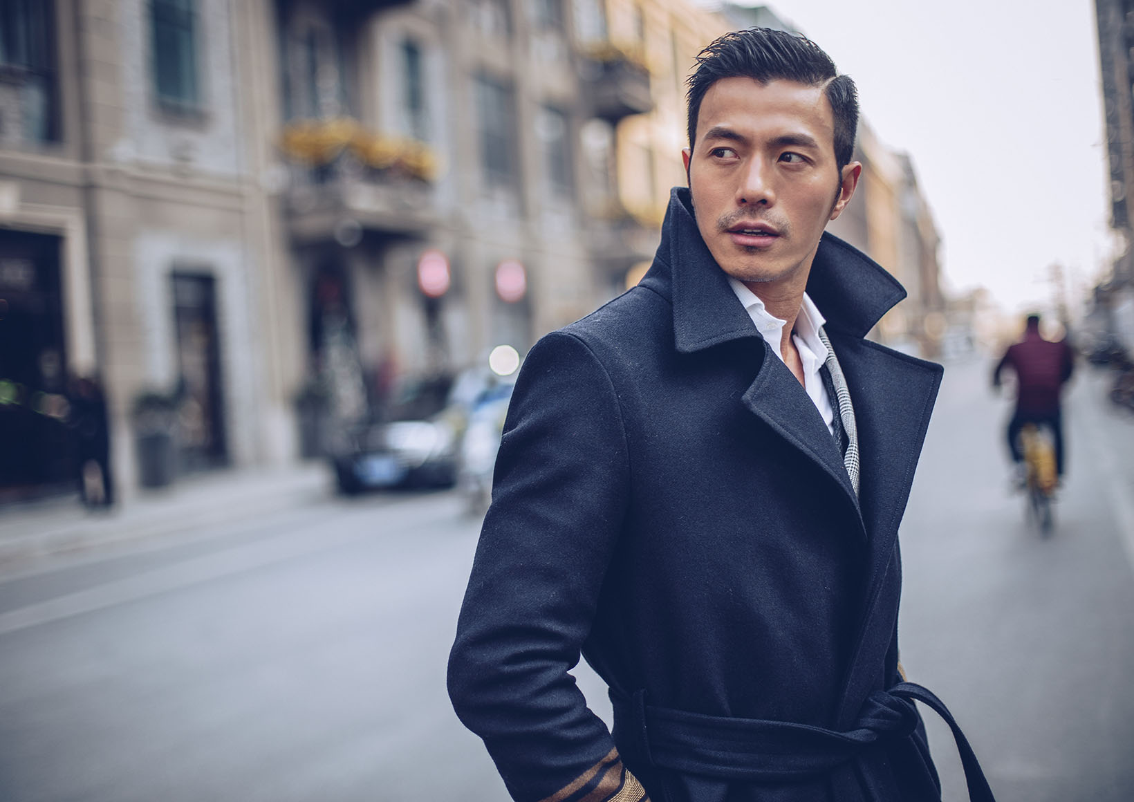 Asian male on a city street in a trench coat